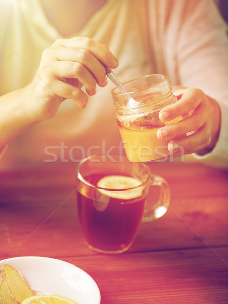 close up of woman adding honey to tea with lemon Stock photo © dolgachov