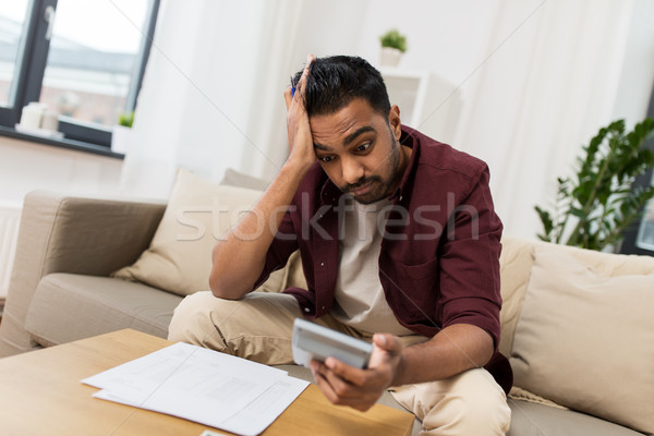 confused man with papers and calculator at home Stock photo © dolgachov