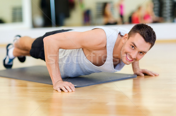 smiling man doing push-ups in the gym Stock photo © dolgachov