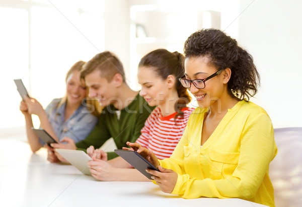 Stock photo: smiling students looking at tablet pc at school