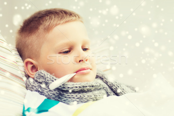 ill boy with thermometer lying in bed at home Stock photo © dolgachov