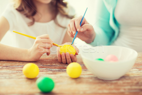 close up of little girl and mother coloring eggs Stock photo © dolgachov