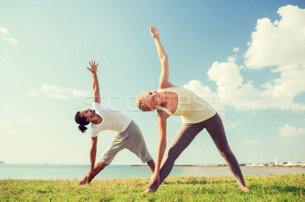 smiling couple making yoga exercises outdoors Stock photo © dolgachov