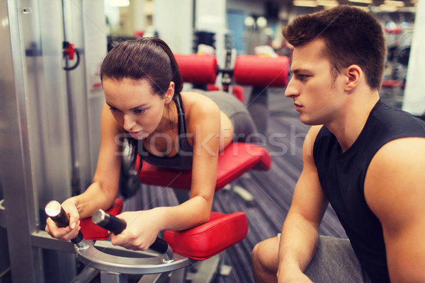 young woman with trainer exercising on gym machine Stock photo © dolgachov