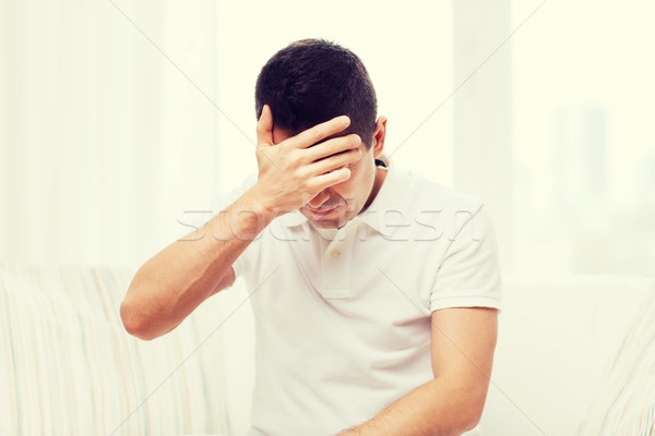 unhappy man suffering from head ache at home Stock photo © dolgachov