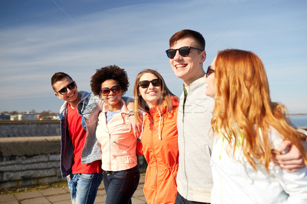 happy teenage friends walking along city street Stock photo © dolgachov