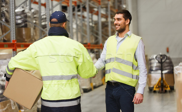 men in safety vests shaking hands at warehouse Stock photo © dolgachov