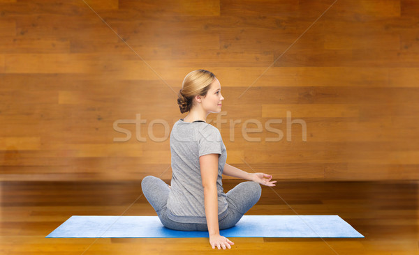 woman making yoga in twist pose on mat Stock photo © dolgachov