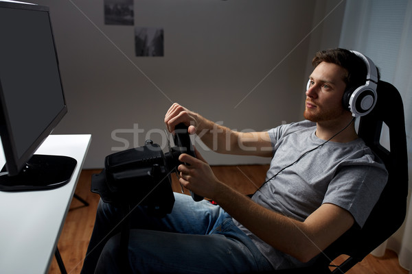 Stock photo: man playing car racing video game at home