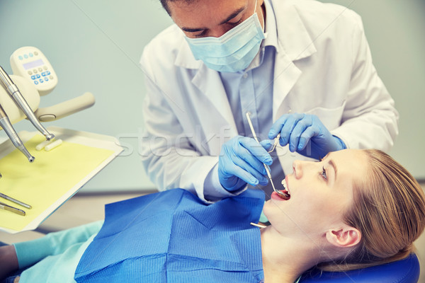 male dentist in mask checking female patient teeth Stock photo © dolgachov