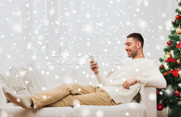 smiling man with smartphone at home for christmas Stock photo © dolgachov