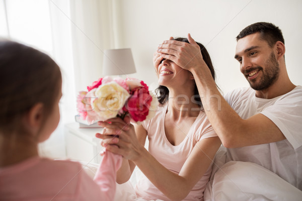 happy girl giving flowers to mother in bed at home Stock photo © dolgachov