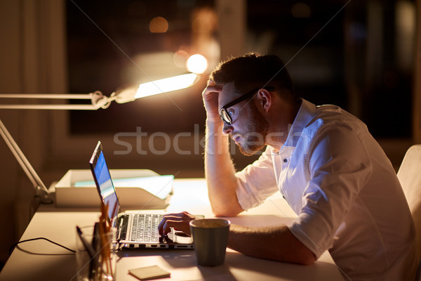 businessman typing on laptop at night office Stock photo © dolgachov