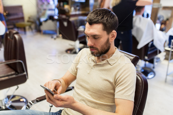 man with smartphone at barbershop or salon Stock photo © dolgachov