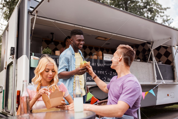 happy friends with drinks eating at food truck Stock photo © dolgachov