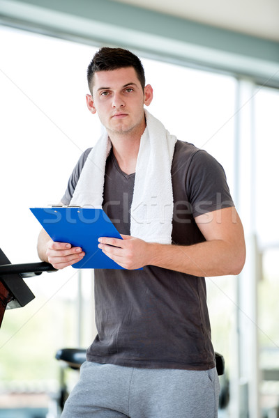 Stock photo: trainer with clipboard standing in a bright gym