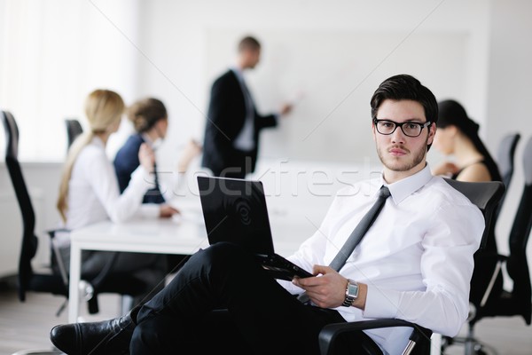 Stock photo: Portrait of a handsome young business man with colleagues in background