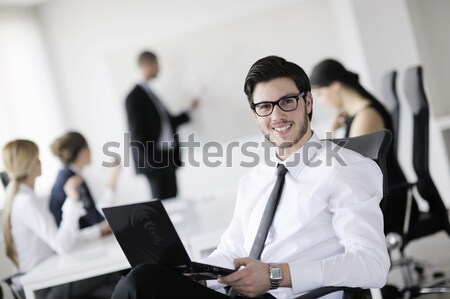 Stock photo: Portrait of a handsome young business man with colleagues in background