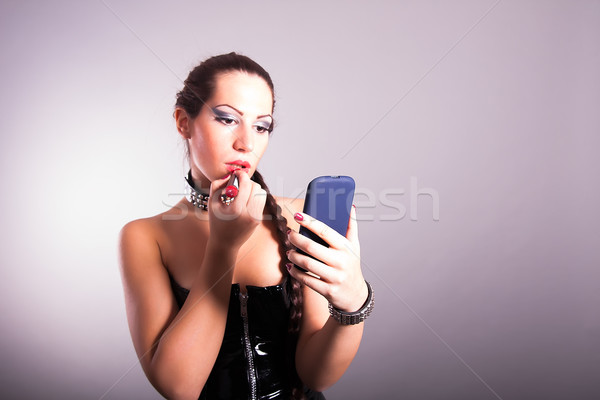 Young woman applying lipstick looking at mirror Stock photo © dukibu