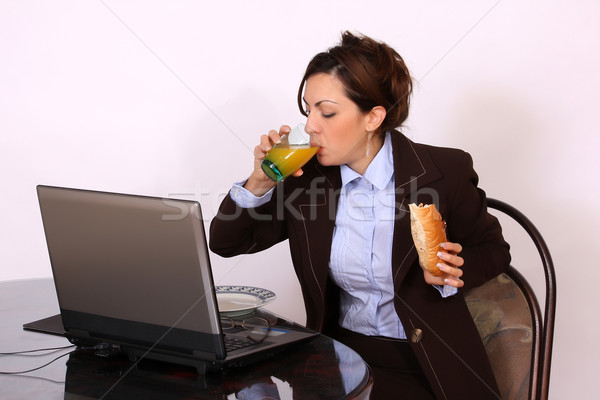 Businesswoman eating by the desk Stock photo © dukibu