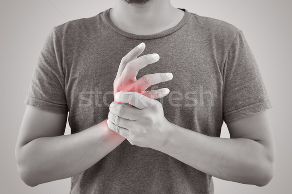 Asian man with pain in wrist against gray background Stock photo © eddows_arunothai