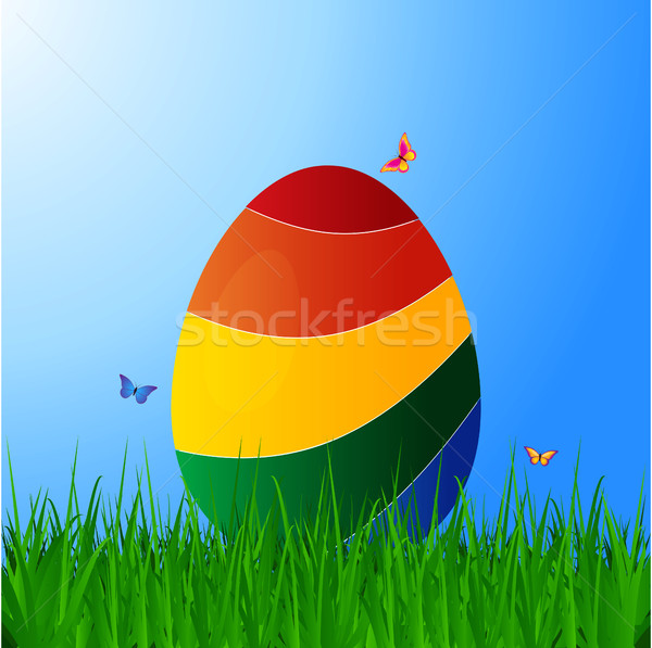 Stock photo: Curved striped Easter egg on grass over blue sky