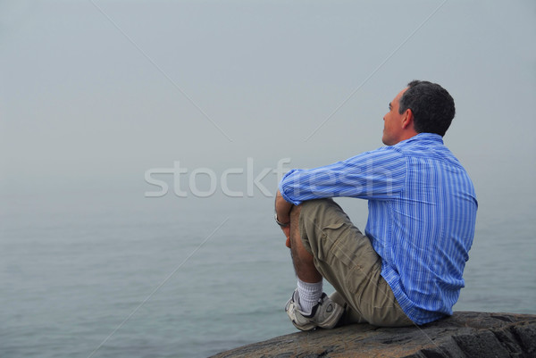 Uomo guardando nebbia seduta shore Foto d'archivio © elenaphoto