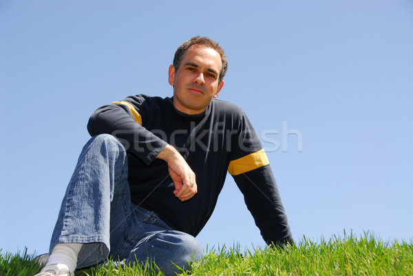 Foto stock: Homem · sessão · grama · sem · nuvens · céu · sorrir