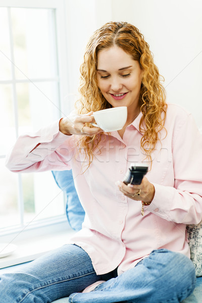 Stock photo: Woman dialing phone and drinking coffee