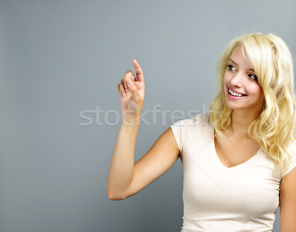 Happy young woman pointing Stock photo © elenaphoto
