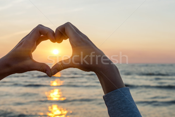 Hands in heart shape framing sun Stock photo © elenaphoto