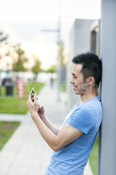 Foto stock: Jóvenes · Asia · hombre · teléfono · celular · sonriendo · mirando