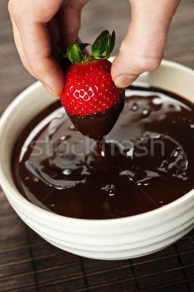Hand dipping strawberry in chocolate Stock photo © elenaphoto