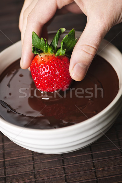 Hand dipping strawberry in chocolate Stock photo © elenaphoto