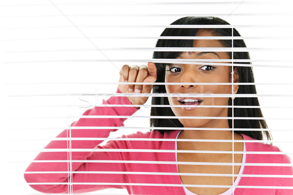 Woman looking through venetian blinds Stock photo © elenaphoto