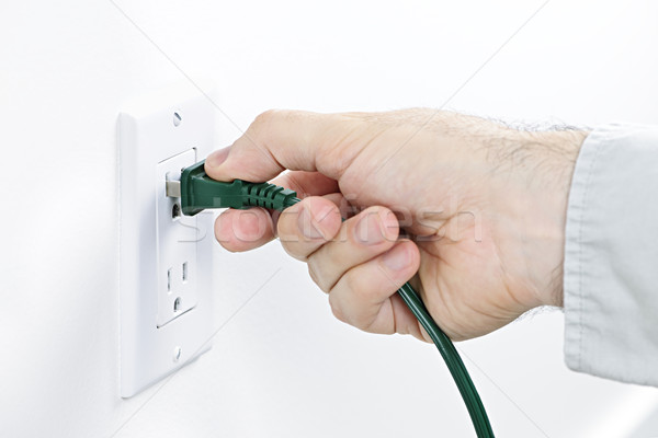 Hand inserting plug into outlet Stock photo © elenaphoto