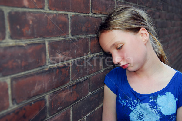 Fille bouleversé jeune fille mur de briques regarder mur Photo stock © elenaphoto