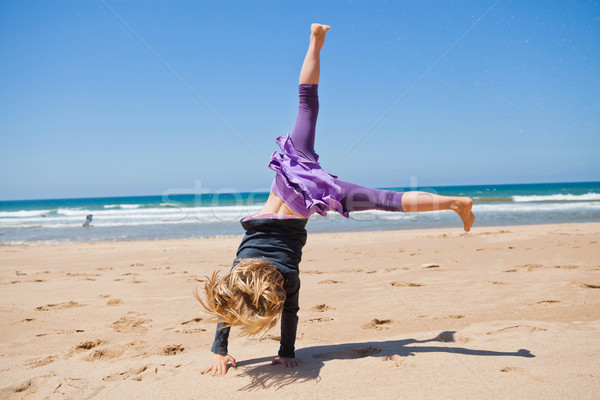 Stock photo: Young girl doing cartwheel at beach