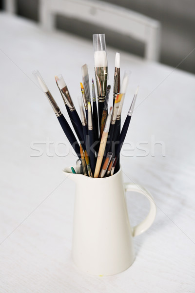 Set of paintbrushes in jug on a table. Stock photo © ElinaManninen