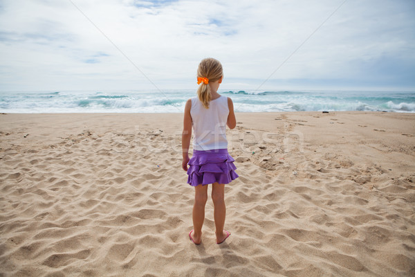 Jong meisje permanente strand strandzand naar oceaan Stockfoto © ElinaManninen