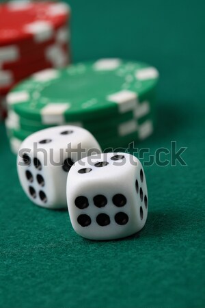 Stock photo: Pair of gambling die and poker chips on a green surface.