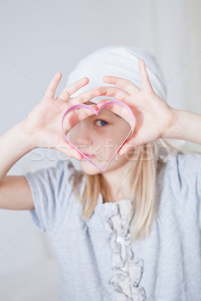 Young girl looking through gingerbread biscuit cutter Stock photo © ElinaManninen