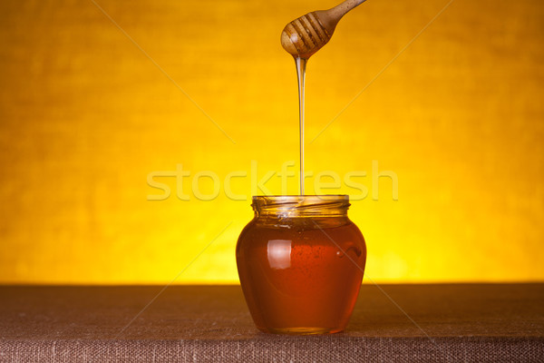 Stock photo: Honey jar with dipper and flowing honey