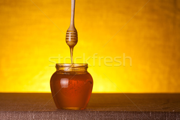 Honey jar with wooden dipper and flowing honey  Stock photo © Elisanth