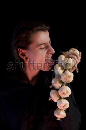 Stock photo: Evil vampire with scary eyes is licking garlic  