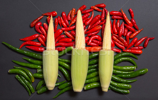 Fresh raw baby corn cobs on red and green non-stem chili peppers Stock photo © Elisanth