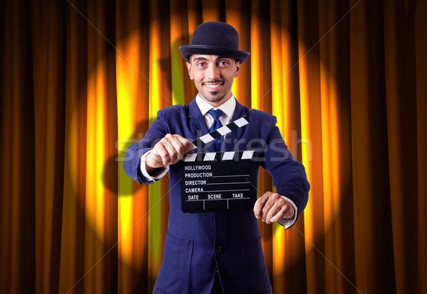 Stock photo: Man with movie clapper on curtain background