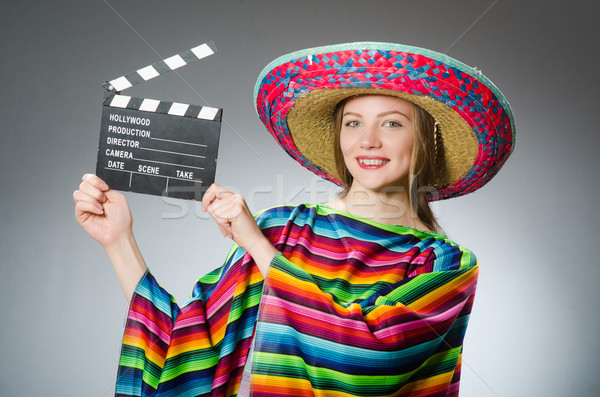 Girl in mexican vivid poncho holding clapboard against gray Stock photo © Elnur