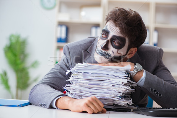 Businessmsn with scary face mask working in office Stock photo © Elnur