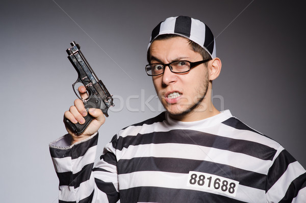 Young prisoner with weapon against gray Stock photo © Elnur